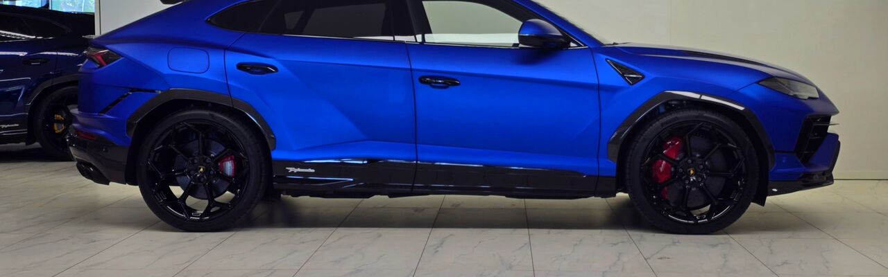 Lamborghini Urus azul visto de lado, sobre fundo claro